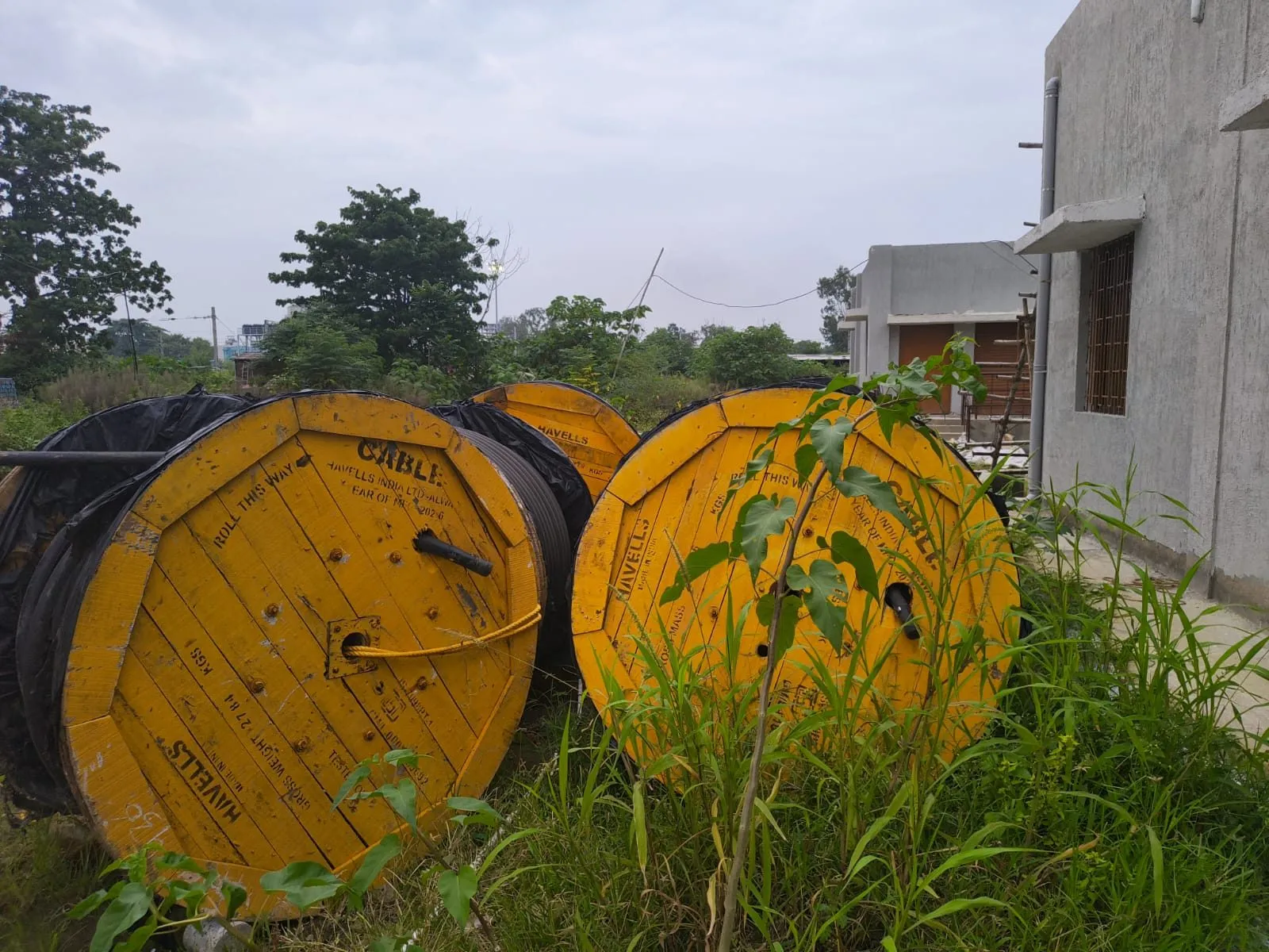 Two large yellow cable drums standing in grass beside a newly built substation building