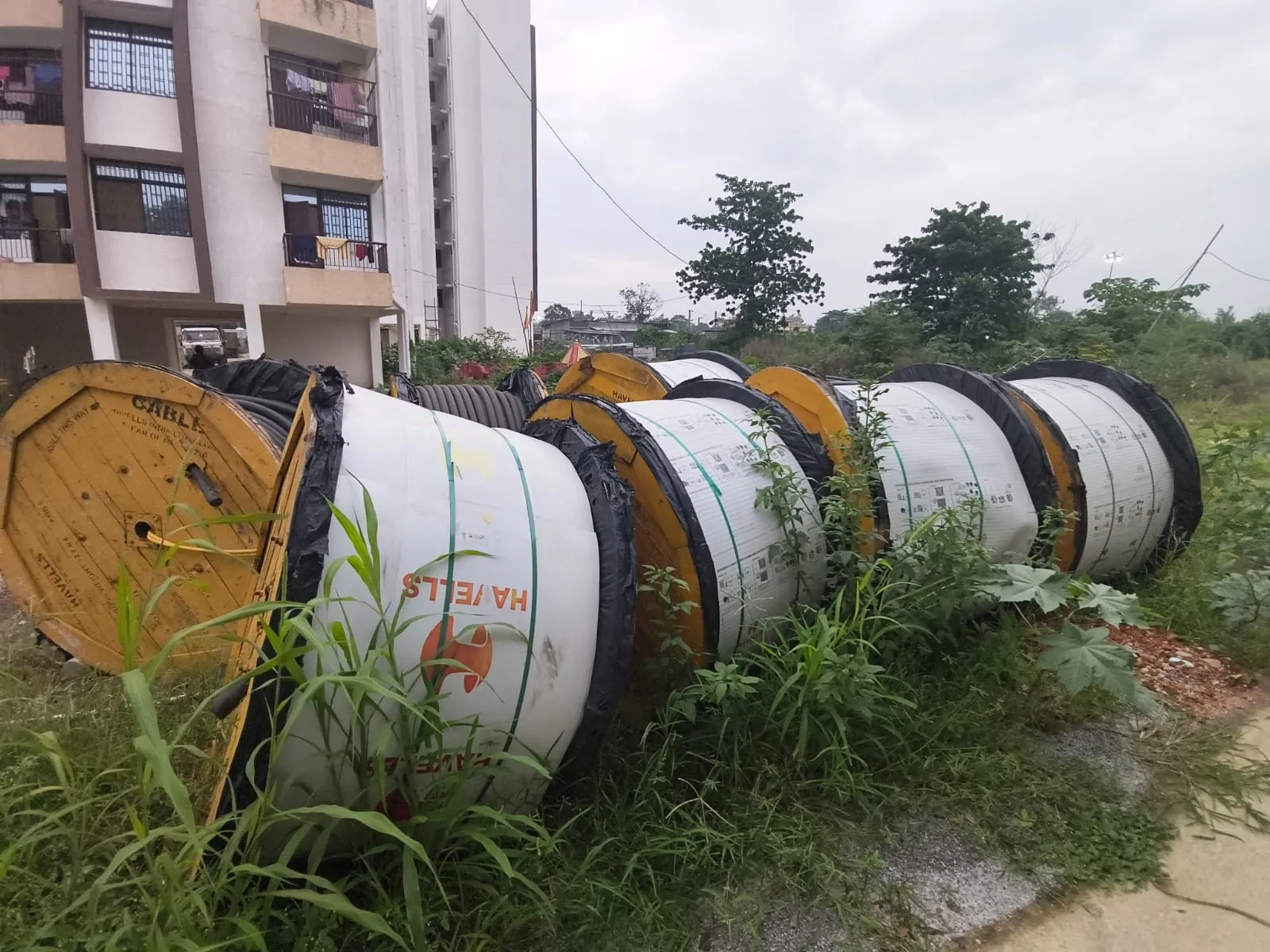 A row of cable drums laid on their sides at the edge of a site, part-run-out