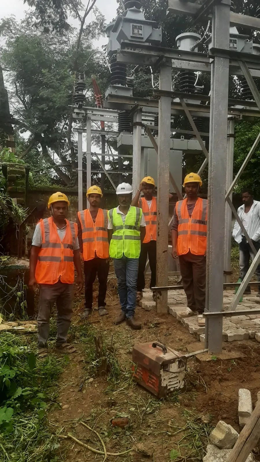 Site crew in high-visibility vests and helmets standing at a completed substation bay