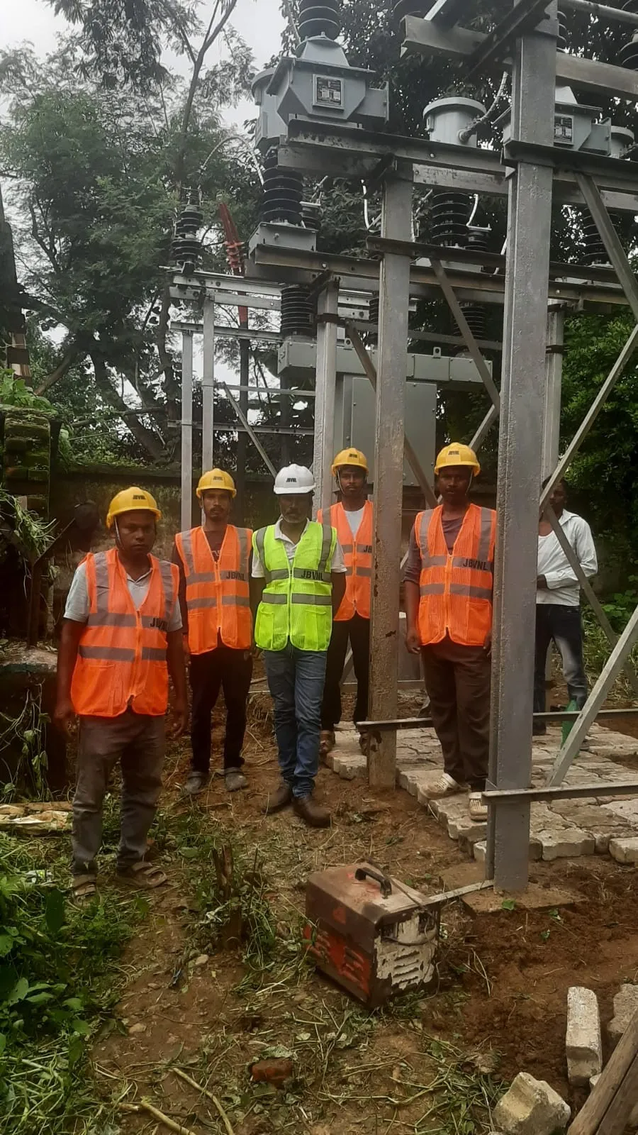 Site crew in high-visibility vests and helmets standing at a partly erected structure