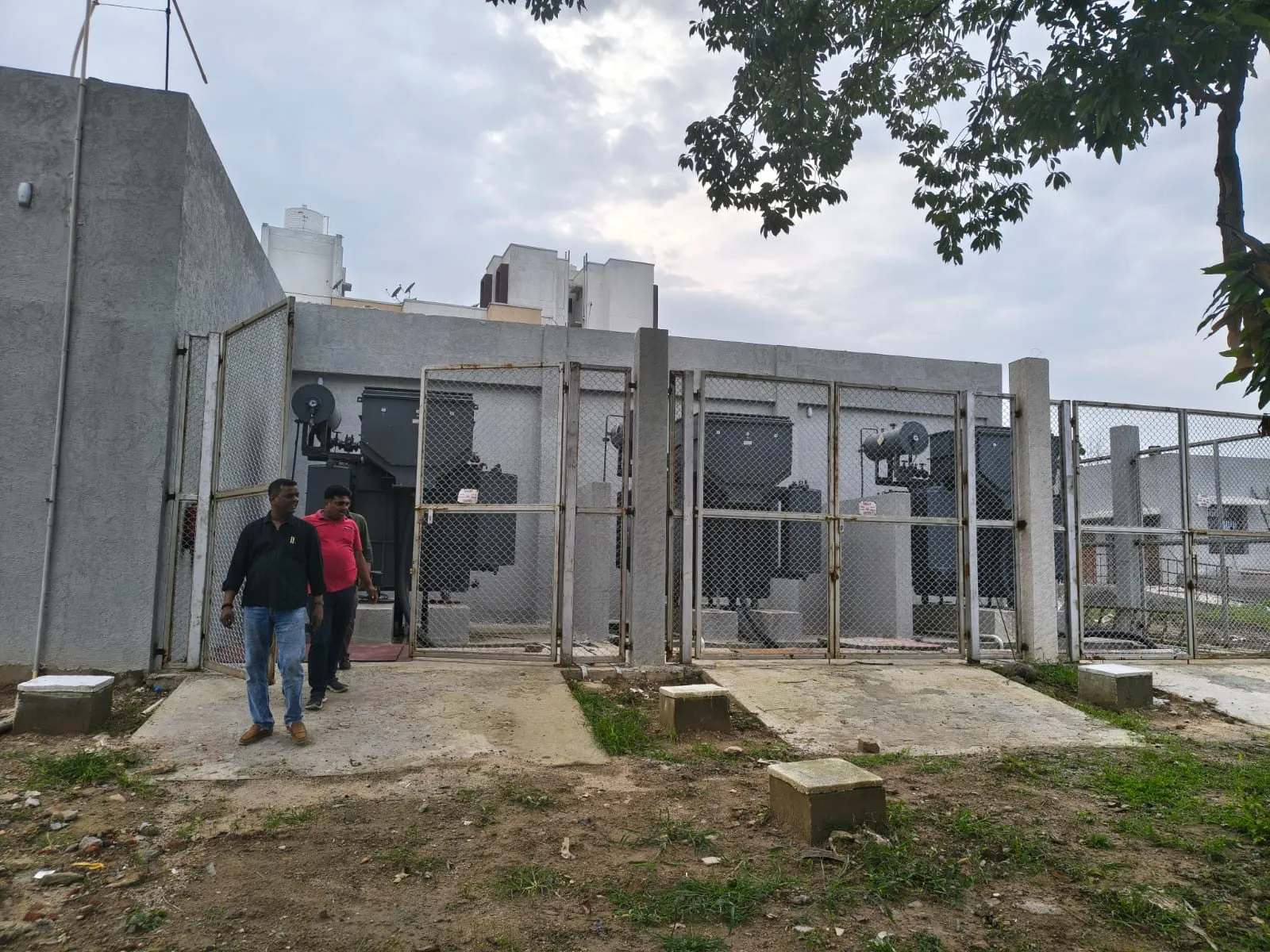 Two Ranisons crew members walking into a fenced substation compound