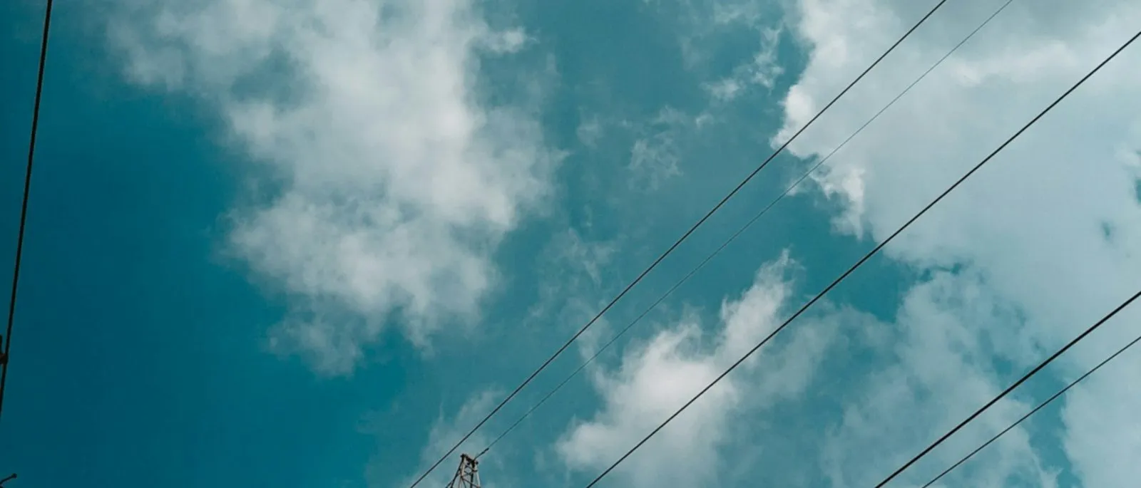 A high-voltage transmission tower and conductors against a cloudy sky