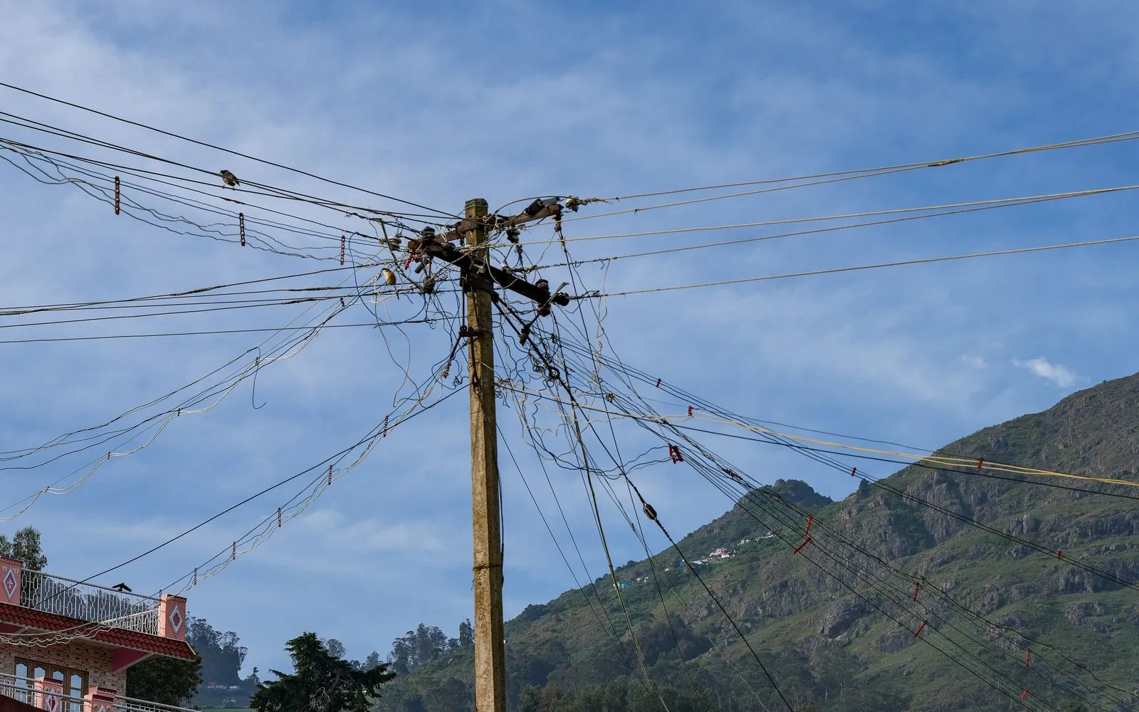 A low-tension distribution pole carrying a fan of service drops over a hillside town