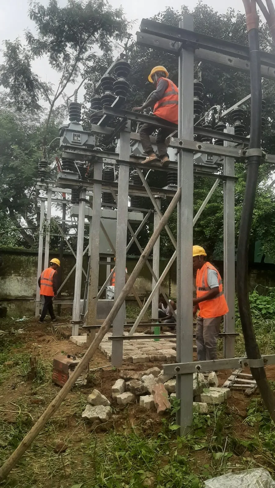 Workers aligning a steel column against a guy pole before it is grouted