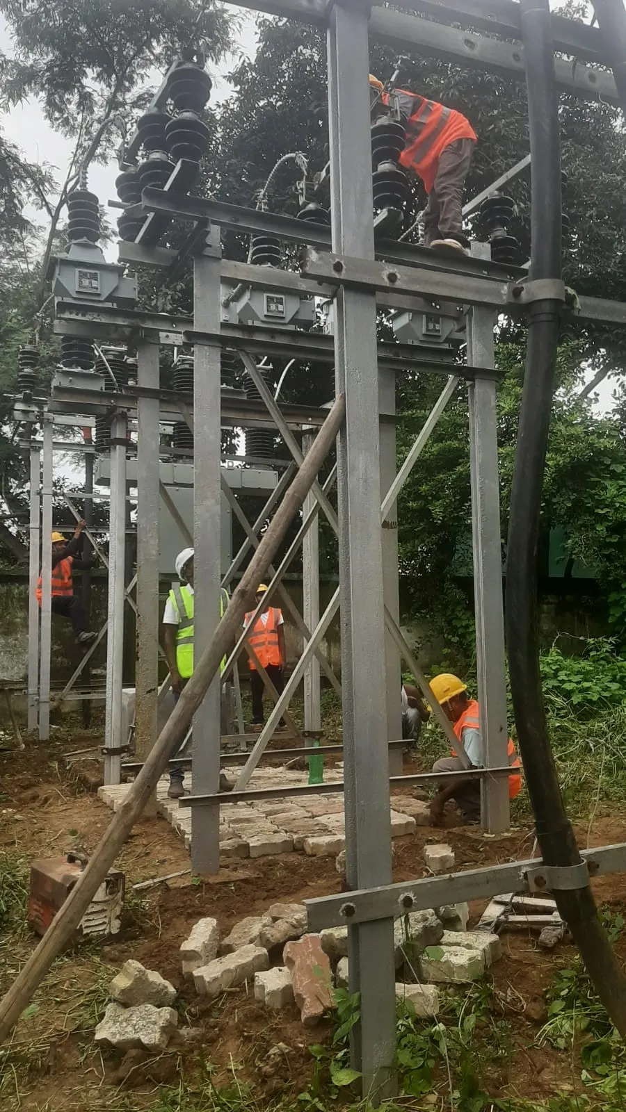 Two workers plumbing a steel structure with a temporary prop
