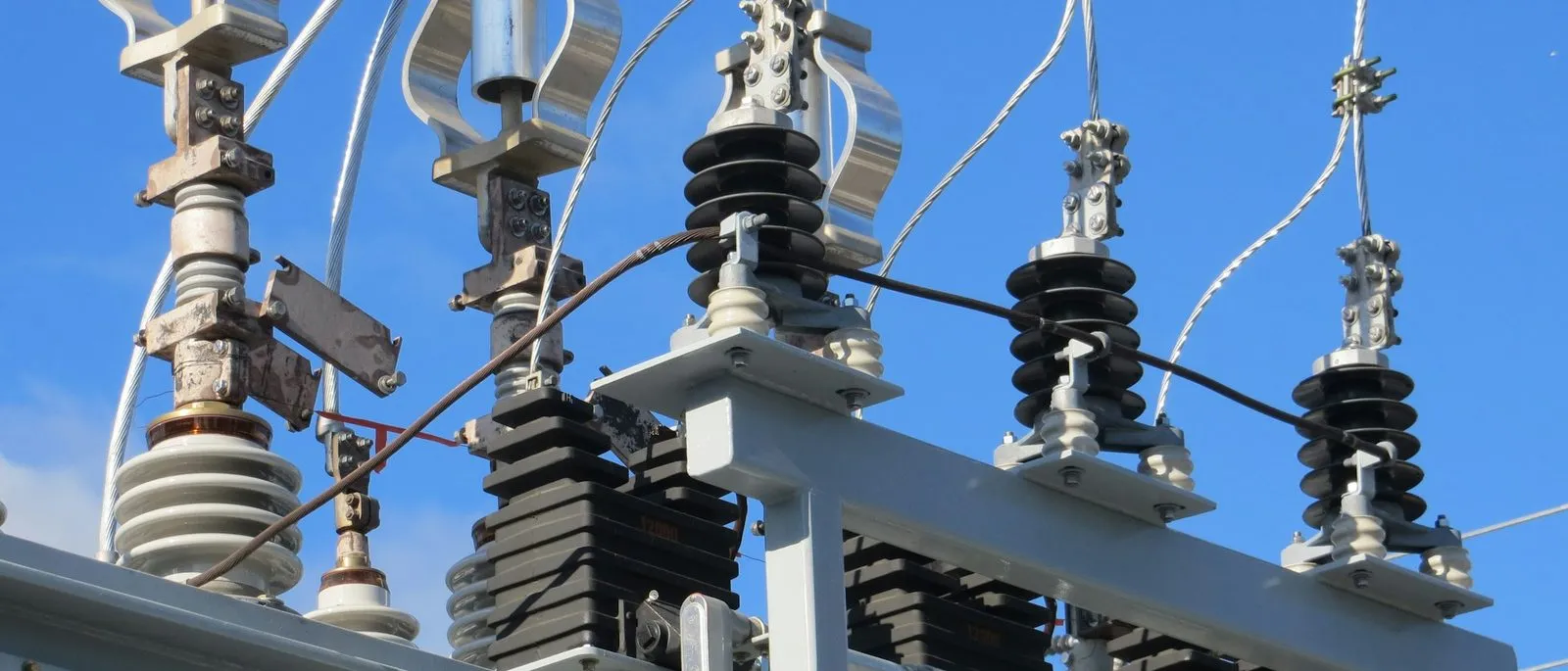 Transformer bushings and lightning arresters against a clear sky