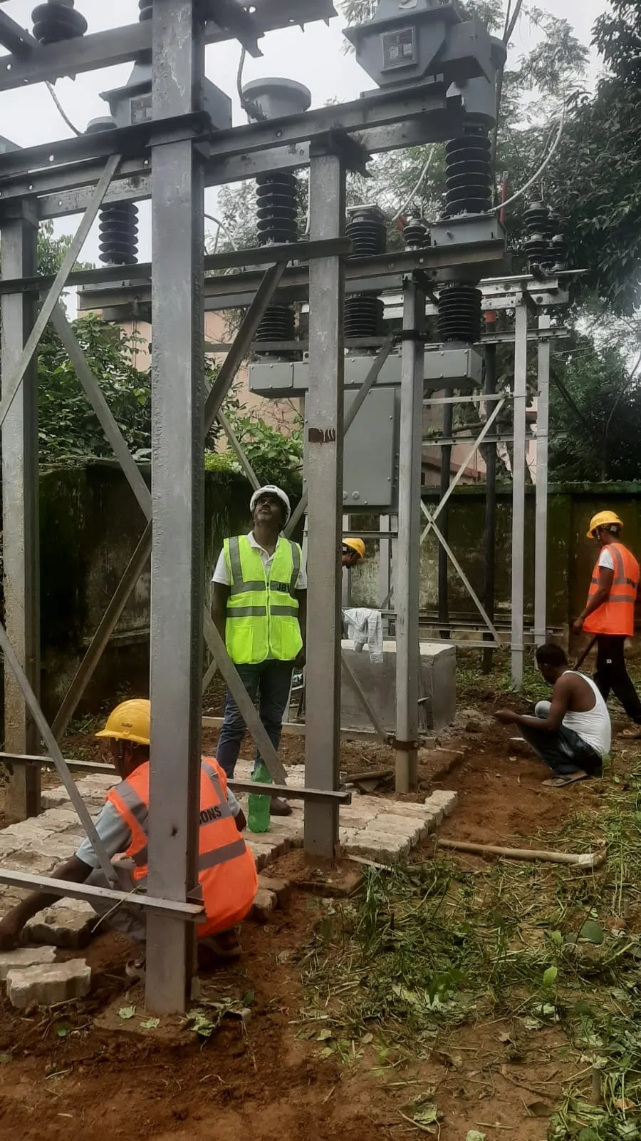 Crew working below installed high-tension switchgear in a substation yard