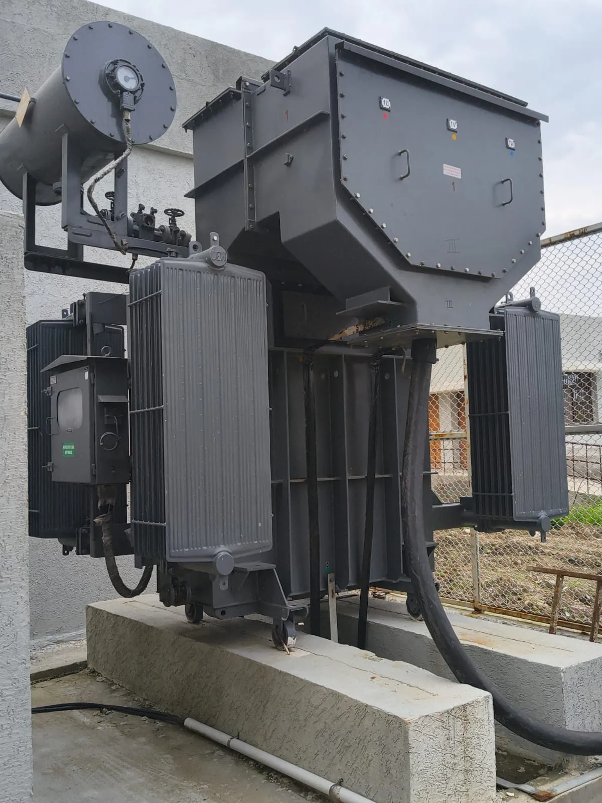 Transformer with conservator tank and Buchholz relay visible above the tank