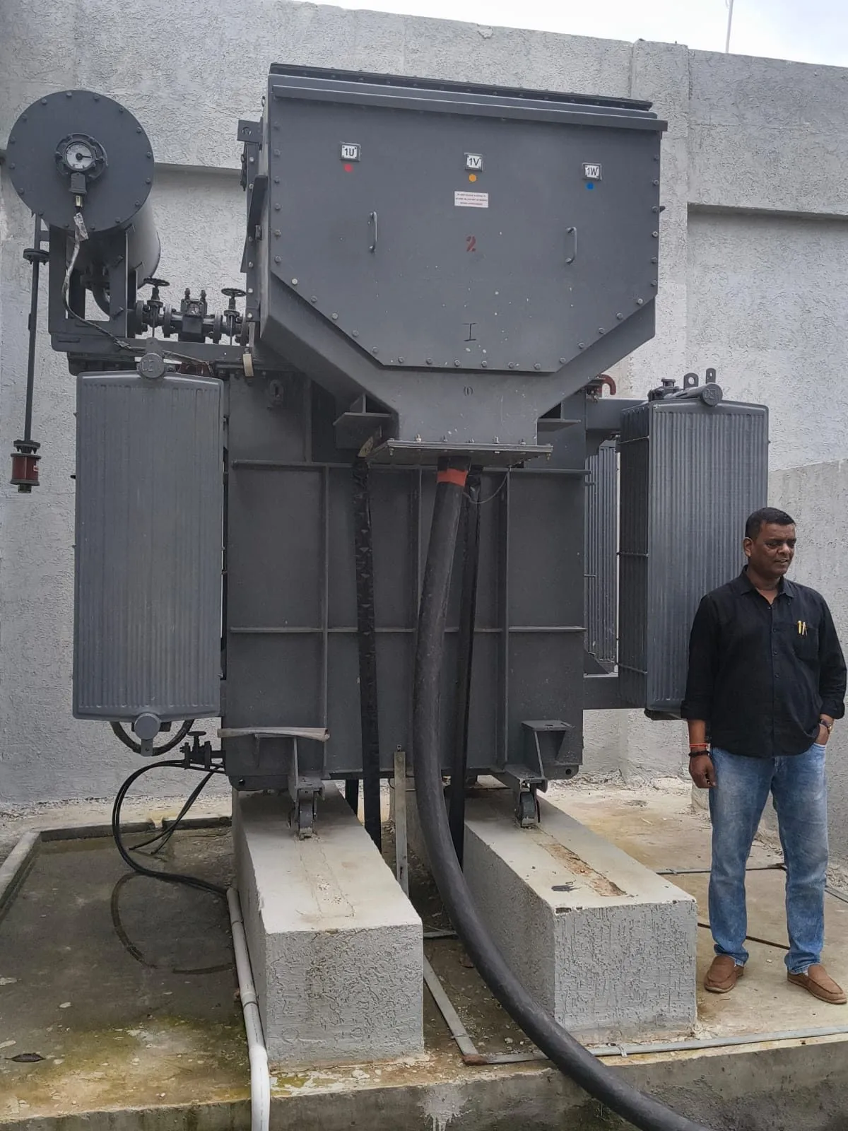 Ranisons crew member standing beside an installed transformer, giving a sense of its height